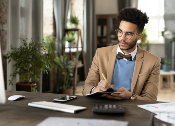 Accountant making notes on a clipboard at his desk