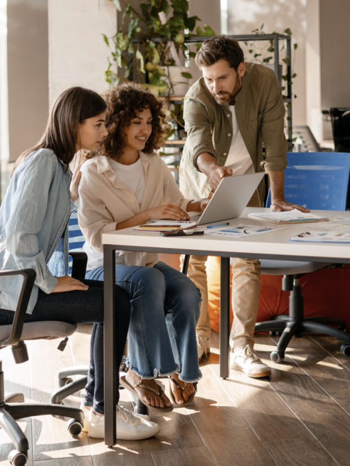 Three colleagues reviewing a payroll run together on a laptop