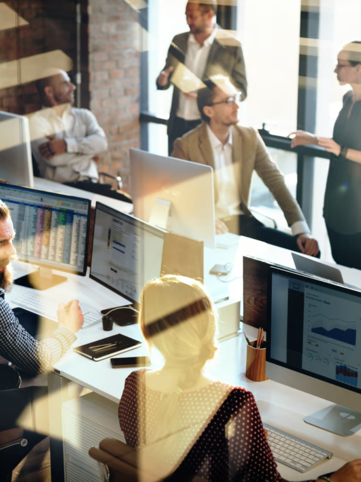 Accountants at multi-monitor desks reviewing corporation tax figures and reports