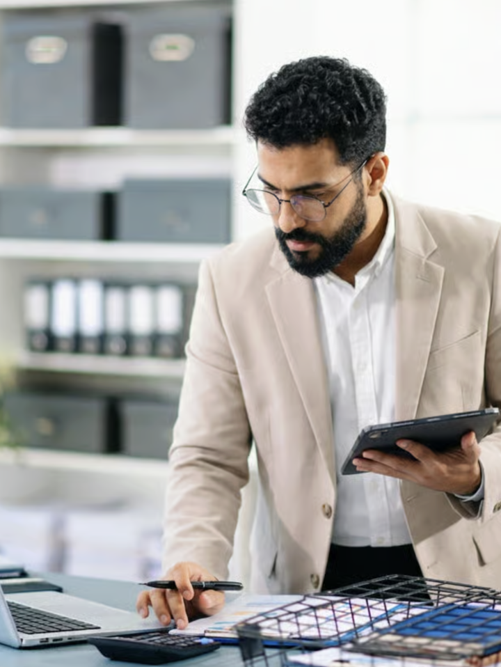 Adviser standing at his desk setting up a new company on a laptop and tablet